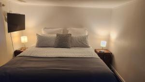 a bedroom with a bed with pillows and two lamps at Beachfront Sunset Bach in Piha
