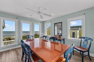 a dining room with a table and chairs and windows at 4099 - 3-2-1 Relax in Duck