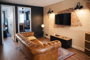 a living room with a leather couch and a flat screen tv at Artist Retro Disneyland Paris P3 in Coutevroult