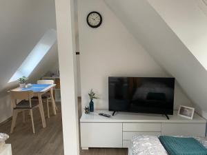 a living room with a tv on a white cabinet with a clock at R&A Unterkunft in Oberhausen