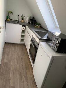 a small kitchen with white cabinets and a wooden floor at R&A Unterkunft in Oberhausen +8 photos