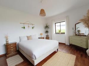 a white bedroom with a white bed and a window at Villa Intuitiva - Relaxation and Mindful Stay in Lourinhã