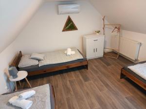 a small bedroom with two beds and a chair at Panoráma Vendégház Jásd in Jásd