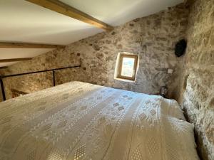a bedroom with a bed in a stone wall at Le Logis - Maison authentique avec jardin et vue panoramique in Mons +28 photos