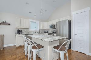 a kitchen with white cabinets and a large island with bar stools at 5176 - Sandy Bottoms in Kill Devil Hills +30 photos