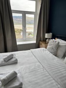 a bedroom with a large white bed with a window at Bryn Melyn Apartments in Barmouth