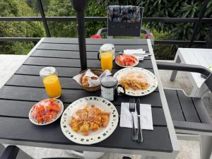 a table with plates of food and two glasses of orange juice at MeNTA GLAMPING in Sasaima