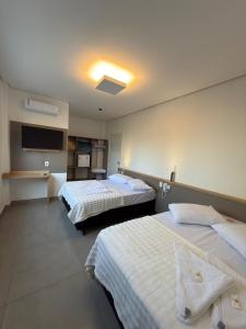 a hotel room with two beds and a tv at Hotel Morais in Lagoa Vermelha