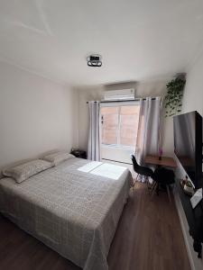 a bedroom with a bed and a television and a window at Apto no Centro de Porto Alegre in Porto Alegre