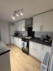 a kitchen with white cabinets and a stove top oven at Silver stays, calm coastal stay , close to beach in Gorleston-on-Sea
