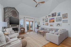 a living room with white furniture and a flat screen tv at 5468 - Mermaids' Lagoon in Nags Head