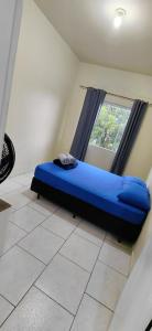 a blue bed in a room with a window at pousada Adriane in Rio do Sul