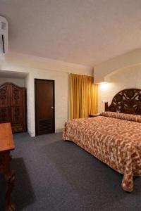 a hotel room with a bed and a door at San Carlos de Reynosa in Reynosa