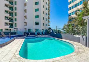 a swimming pool in front of a building at Classic Coastal Escape - 1 Bedroom Ocean Views in Maroochydore