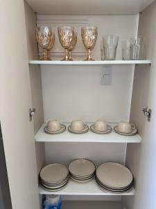 a cupboard filled with plates and bowls and glasses at Dona Olivia Universidade 08 in Vitória da Conquista