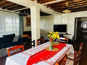 a dining room table with a vase of flowers on it at KFarm house in Kijabe