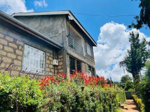 a brick house with red flowers in front of it at KFarm house in Kijabe
