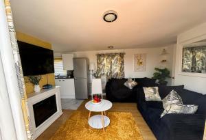 a living room with a blue couch and a tv at Sun, Sand & Sheppey The Ultimate Escape in Leysdown-on-Sea +5 photos