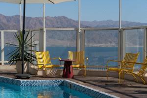 a pool with chairs and a table next to the water at Kedem Eilat קדם אילת in Eilat