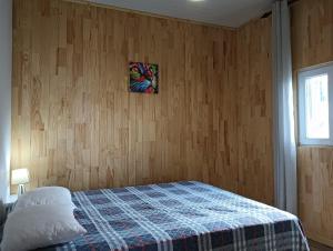 a bedroom with a bed and a wooden wall at Lombada Villa Comfort in Ponta Delgada