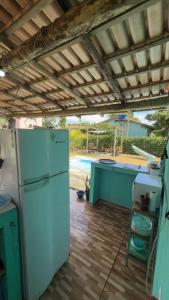 a kitchen with a white refrigerator and a table at Pousada Villa Maria Corumbau in Corumbau