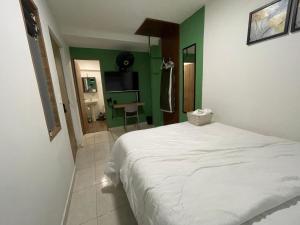a bedroom with a white bed and a green wall at Olivo House Casa Hotel in Envigado