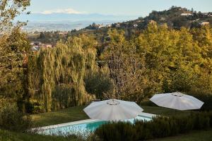 two white umbrellas sitting next to a swimming pool at Vigne dei Mastri in Costigliole dʼAsti