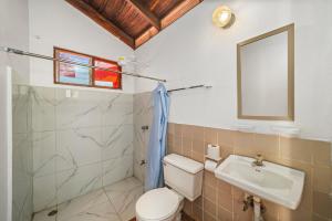 a bathroom with a toilet and a sink and a mirror at Hotel Hibiscus in Playa Junquillal