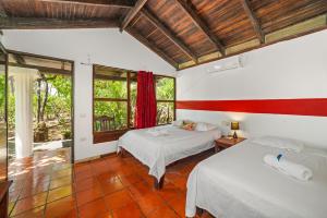 a bedroom with two beds and a window at Hotel Hibiscus in Playa Junquillal