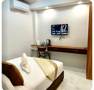 a bedroom with a bed and a desk with a tv at KJSGrandeInn in Manolo Fortich