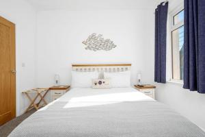 a bedroom with a large white bed with blue curtains at Mournes Hot Tub Retreat, 4-Star Accommodation in Newcastle