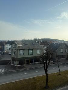 a house on the side of a road with a tree at Central Top Floor Apartment in Stavanger