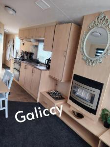 a kitchen with a fireplace and a mirror on the wall at Caravan Galiccy in Kinmel Bay +3 photos