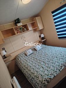 a small bedroom with a bed and shelves at Caravan Galiccy in Kinmel Bay