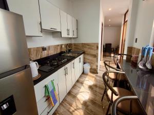 a kitchen with white cabinets and a counter with chairs at Huacachina Desert II in Ica