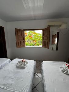 a room with two beds with a window and a mirror at Pousada Nativa - Vista ao mar in Ilha de Boipeba