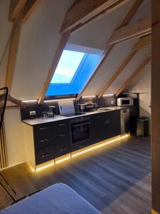 an attic kitchen with black cabinets and a window at Moderne Dachgeschosswohnung am Wald in Großnaundorf