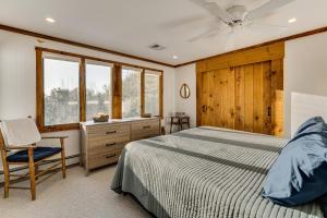 a bedroom with a bed and a chair and windows at Resort-Style Community! Quechee Chalet w/ Deck in Quechee