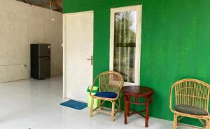 two chairs and a table in a room with a green wall at The Green Pearl Paradise in Biluhu