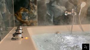 a bath tub filled with water with a faucet at LE 21 - Suite SPA Premium - Jacuzzi Privatif & Vue Rhône in Vienne