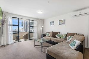 a living room with a couch and a glass table at Ocean Seascape - Mt Maunganui in Mount Maunganui