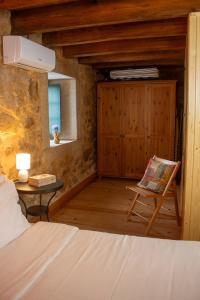 a bedroom with a bed and a chair and a table at Refugio dos Cartolas - Mountain Retreat in São Mamede +53 photos