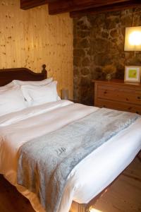 a large bed in a room with a stone wall at Refugio dos Cartolas - Mountain Retreat in São Mamede