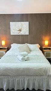 a bedroom with a white bed with two towels on it at Hostal Like Home in Puerto Natales