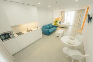 a white living room with a blue couch and a table at Apartamentos Aires de Conil in Conil de la Frontera