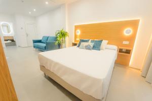 a bedroom with a large bed and a blue chair at Apartamentos Aires de Conil in Conil de la Frontera +33 photos