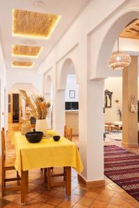 a dining room with a table with a yellow table cloth at Miguirne Chez Ali Dades in Tamellalt
