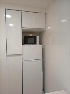a white kitchen with a microwave on top of a refrigerator at Las Meanas Presbítero 6 in Avilés