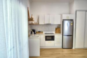 a kitchen with white cabinets and a stainless steel refrigerator at Solis in Agnes Water in Agnes Water