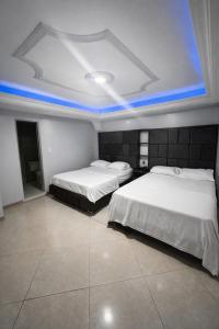 two beds in a room with blue lights on the ceiling at Hotel calima royal in Cali